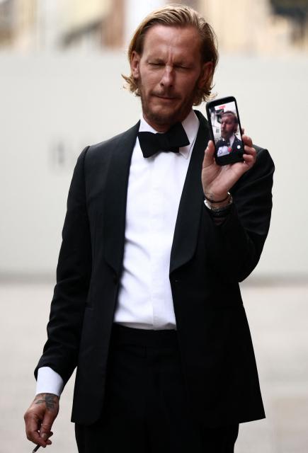 British actor-turned-politician/activist Laurence Fox gestures with his phone, live-streaming, as he stands behind  security barriers after arriving to attend a speech by British far-right activist Tommy Robinson, real name Stephen Yaxley-Lennon, to The Oxford Union, in Oxford, western England, on June 17, 2026. (Photo by Henry NICHOLLS / AFP)