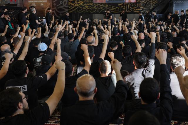 People react as Hezbollah Secretary-General Sheikh Naim Qassem addresses crowds via a giant screen during the first day of Ashura commemorations at the mausoleum of former Hezbollah leader Hassan Nasrallah in Beirut’s southern suburbs on June 17, 2026. Qassem said on June 17 that Lebanon's negotiations with Israel should be limited to "mutual security", and that the country's main demand should be restoring its sovereignty after Israeli troops invaded the south. (Photo by Anwar AMRO / AFP)