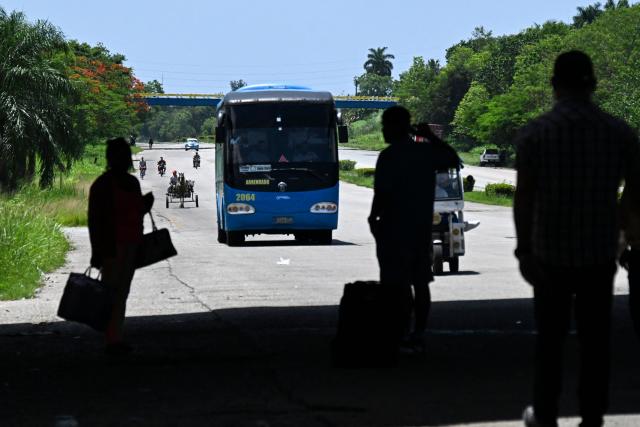 People wait for a bus on the National Highway, on the outskirts of Havana on June 16, 2026. New restrictions on interprovincial transport in Cuba come into force on June 18, 2026, with trains running every 16 days, few weekly coaches and a state system for allocating tickets according to criteria of "urgency", amid a severe fuel shortage, under pressure from Washington. (Photo by YAMIL LAGE / AFP)