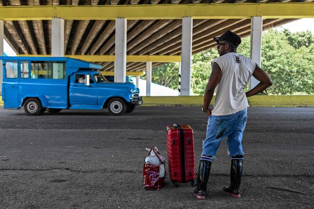 A man stands next to his luggage waiting for transport on the National Highway, on the outskirts of Havana on June 16, 2026. New restrictions on interprovincial transport in Cuba come into force on June 18, 2026, with trains running every 16 days, few weekly coaches and a state system for allocating tickets according to criteria of "urgency", amid a severe fuel shortage, under pressure from Washington. (Photo by YAMIL LAGE / AFP)