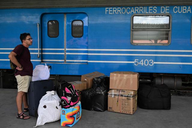 A man stands besides luggage and stacked boxes on a platform in front of a carriage of a Ferrocarriles de Cuba train, in Havana on June 16, 2026. New restrictions on interprovincial transport in Cuba come into force on June 18, 2026, with trains running every 16 days, few weekly coaches and a state system for allocating tickets according to criteria of "urgency", amid a severe fuel shortage, under pressure from Washington. (Photo by YAMIL LAGE / AFP)