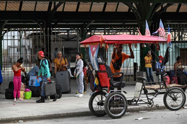 People stand next to their luggage outside the Ferrocarriles de Cuba train station in Havana on June 16, 2026. New restrictions on interprovincial transport in Cuba come into force on June 18, 2026, with trains running every 16 days, few weekly coaches and a state system for allocating tickets according to criteria of "urgency", amid a severe fuel shortage, under pressure from Washington. (Photo by YAMIL LAGE / AFP)