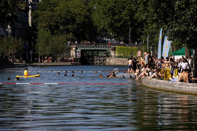 A lifeguard  watches over swimmers the Canal Saint-Martin in Paris on June 17, 2026. France braced for another heat wave on June 17, with Paris allowing swimming in one of its canals so residents could cope with the heat. (Photo by JOEL SAGET / AFP)