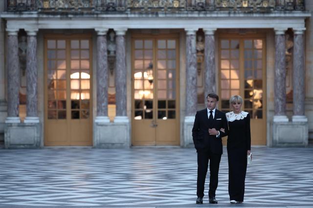 France's President Emmanuel Macron (L) and his wife Brigitte Macron (R) await the arrival of US President Donald Trump (not pictured) ahead of a dinner to celebrate the 250th anniversary of the independence of the United States, at Chateau de Versailles in Versailles southwest of Paris on June 17, 2026. (Photo by Guillaume BAPTISTE / AFP)