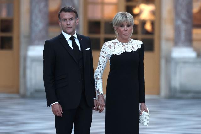 France's President Emmanuel Macron (L) looks on as he awaits the arrival of US President Donald Trump (not pictured) alongside his wife Brigitte Macron (R) ahead of a dinner to celebrate the 250th anniversary of the independence of the United States, at Chateau de Versailles in Versailles southwest of Paris on June 17, 2026. (Photo by Guillaume BAPTISTE / AFP)