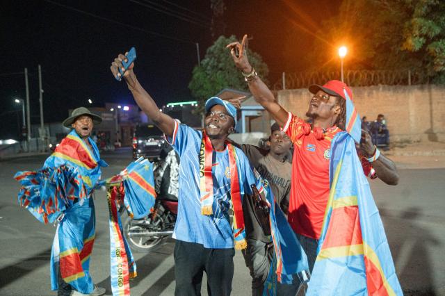 Congolese supporters dressed in the colors of the Democratic Republic of Congo's national flag celebrate the Leopards' equalizing goal in a street in Bunia at night during a FIFA World Cup match between DR Congo and Portugal in Bunia, Ituri Province, Democratic Republic of Congo, on June 17, 2026. The Congolese Leopards played their first match of the tournament in Houston, Texas (United States), against Portugal (1–1). The Democratic Republic of Congo (DRC) had last qualified for a World Cup in 1974. The country was then called Zaire, and the dictator Mobutu Sese Seko was in power (1965–1997). At nightfall in downtown Bunia, the capital of Ituri (northeast), a crowd gathered in the street, standing in front of a modest television screen. Above a barbecue where skewers sold individually were grilling, the owner of a small stall had hung up a screen so people could watch the match. (Photo by Jospin Mwisha / AFP)