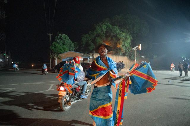 Congolese supporters dressed in the colors of the Democratic Republic of Congo's national flag celebrate the Leopards' equalizing goal in a street in Bunia at night during a FIFA World Cup match between DR Congo and Portugal in Bunia, Ituri Province, Democratic Republic of Congo, on June 17, 2026. The Congolese Leopards played their first match of the tournament in Houston, Texas (United States), against Portugal (1–1). The Democratic Republic of Congo (DRC) had last qualified for a World Cup in 1974. The country was then called Zaire, and the dictator Mobutu Sese Seko was in power (1965–1997). At nightfall in downtown Bunia, the capital of Ituri (northeast), a crowd gathered in the street, standing in front of a modest television screen. Above a barbecue where skewers sold individually were grilling, the owner of a small stall had hung up a screen so people could watch the match. (Photo by Jospin Mwisha / AFP)