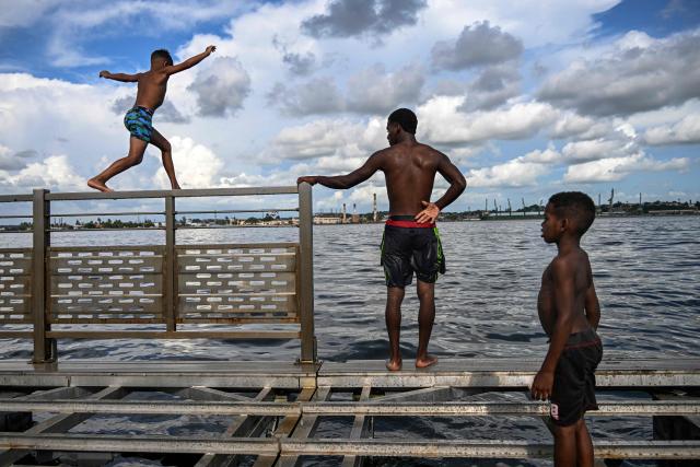 Young people jump into the water from a partially dismantled floating dock in Havana Bay on June 17, 2026. (Photo by YAMIL LAGE / AFP)