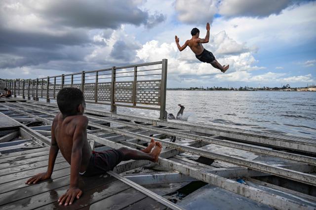 Young people jump into the water from a partially dismantled floating dock in Havana Bay on June 17, 2026. (Photo by YAMIL LAGE / AFP)