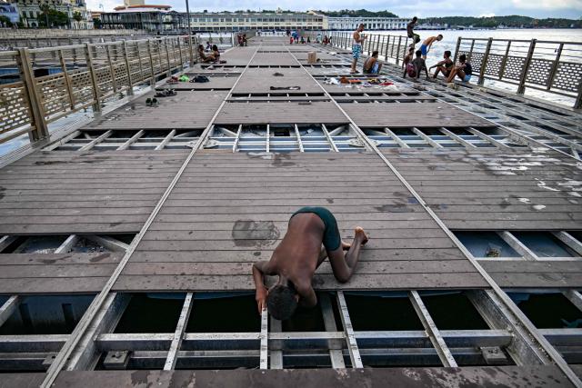 Young people spend time on a partially dismantled floating dock in Havana Bay on June 17, 2026. (Photo by YAMIL LAGE / AFP)