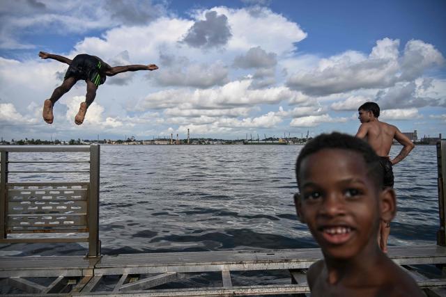 Young people jump into the water from a partially dismantled floating dock in Havana Bay on June 17, 2026. (Photo by YAMIL LAGE / AFP)