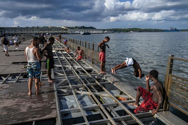 Young people jump into the water from a partially dismantled floating dock in Havana Bay on June 17, 2026. (Photo by YAMIL LAGE / AFP)