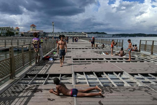 Young people spend time on a partially dismantled floating dock in Havana Bay on June 17, 2026. (Photo by YAMIL LAGE / AFP)