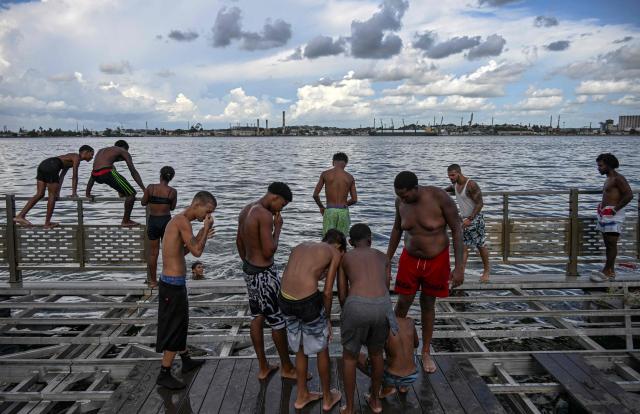 Young people spend time on a partially dismantled floating dock in Havana Bay on June 17, 2026. (Photo by YAMIL LAGE / AFP)