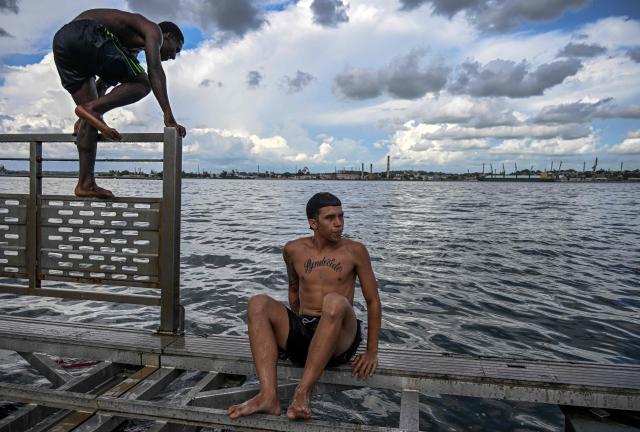 Young people jump into the water from a partially dismantled floating dock in Havana Bay on June 17, 2026. (Photo by YAMIL LAGE / AFP)