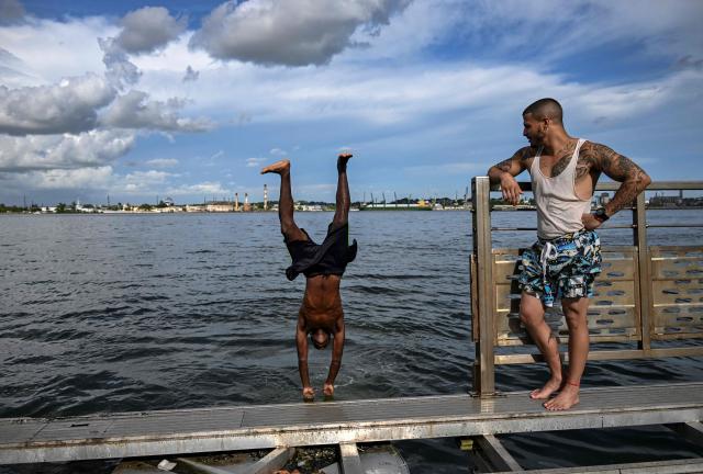 Young people jump into the water from a partially dismantled floating dock in Havana Bay on June 17, 2026. (Photo by YAMIL LAGE / AFP)