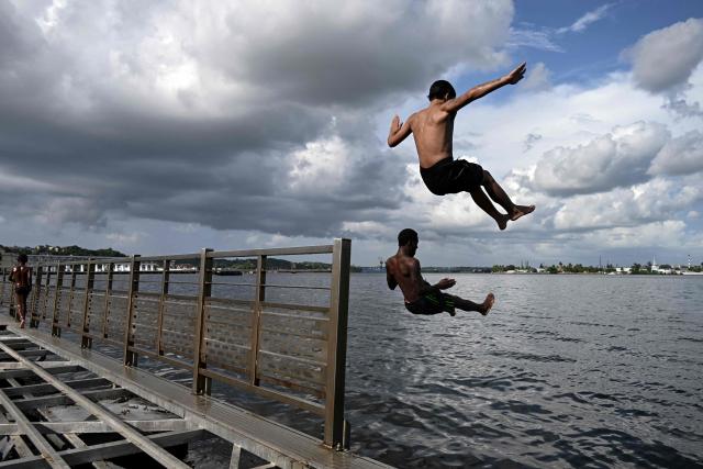 Young people jump into the water from a partially dismantled floating dock in Havana Bay on June 17, 2026. (Photo by YAMIL LAGE / AFP)