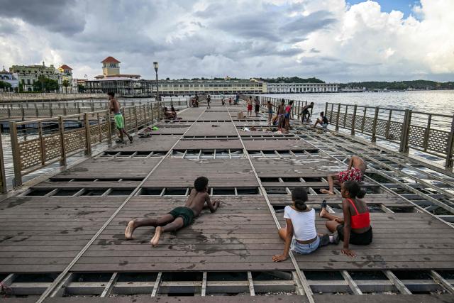 Young people sit and lie on a partially dismantled floating dock in Havana Bay on June 17, 2026. (Photo by YAMIL LAGE / AFP)