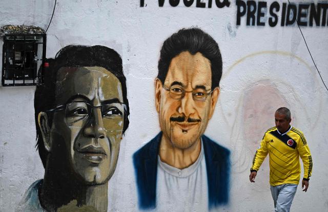 A man walks past a mural painting of Colombia's presidential candidate for the Pacto Historico party Ivan Cepeda, at Ciudad Bolivar neighbourhood, in southern Bogota, on June 17, 2026. Colombians vote on June 21, 2026 in a presidential runoff pitting a hard-right opera-singer-turned-lawyer against a leftist senator, an election with stark consequences for the country's stumbling peace process with armed groups and strained ties with Washington. (Photo by Juan BARRETO / AFP)