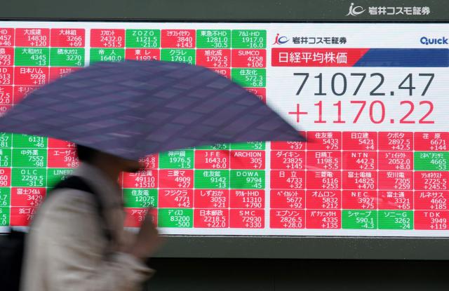 A man walks past an electronic quotation board displaying the Nikkei Stock Average on the Tokyo Stock Exchange in Tokyo on June 18, 2026. (Photo by Kazuhiro NOGI / JIJI PRESS / AFP) / Japan OUT