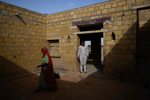 This photograph taken on May 29, 2026 shows herdsman Sawai Singh Bhati (R) standing inside his house in Sanwata village on the outskirts of Rajasthan's Jaisalmer city. In India's hot plains, scorching summers have become increasingly harder to endure, requiring adaptations and forcing life into the hours of dark before the sun turns punishing. Temperatures in Singh's Sanwata village hit 45C in early June, as is often during the summer with the highest temperature recorded in the area as 49C. (Photo by Manan VATSYAYANA / AFP)