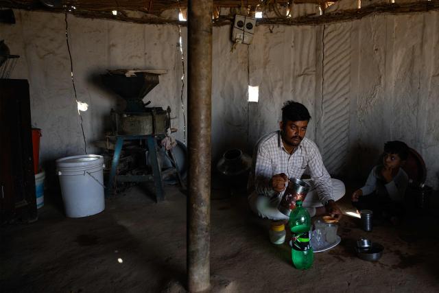 This photograph taken on May 29, 2026 shows herdsman Sawai Singh Bhati (L) preparing lemonade inside a mud-kitchen in 40 degrees Celsius temperatures, outside his house in Sanwata village on the outskirts of Rajasthan's Jaisalmer city. In India's hot plains, scorching summers have become increasingly harder to endure, requiring adaptations and forcing life into the hours of dark before the sun turns punishing. Temperatures in Singh's Sanwata village hit 45C in early June, as is often during the summer with the highest temperature recorded in the area as 49C. (Photo by Manan VATSYAYANA / AFP)