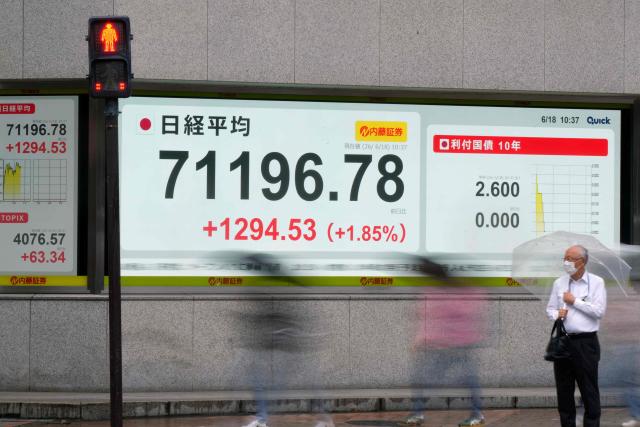 Pedestrians walk past an electronic quotation board displaying the Nikkei Stock Average on the Tokyo Stock Exchange in Tokyo on June 18, 2026. (Photo by Kazuhiro NOGI / AFP)