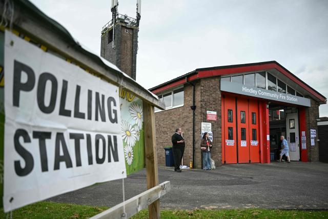 A man (far R) walks into a makeshift polling station set up at a fire station in Hindley, part of the parliamentary constituency for the Makerfield by-election, after the polls opened at 7am on June 18, 2026. Britain holds a unique vote on June 18 that could trigger the endgame for Labour leader Keir Starmer's beleaguered premiership, or win him a reprieve. (Photo by Oli SCARFF / AFP)