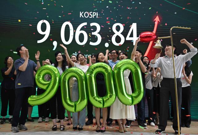 Currency dealers celebrate in front of a screen showing South Korea's benchmark stock index (KOSPI) during a ceremony celebrating it breaking 9,000 points in a foreign exchange dealing room at the Hana Bank headquarters in Seoul on June 18, 2026. South Korea's benchmark Kospi index topped 9,000 points for the first time on June 18, on the back of a tech-fuelled rally led by chip titans Samsung and SK hynix. (Photo by Jung Yeon-je / AFP)