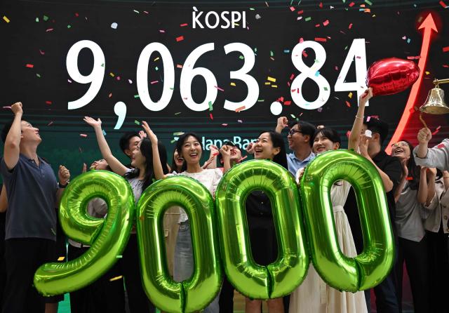Currency dealers celebrate in front of a screen showing South Korea's benchmark stock index (KOSPI) during a ceremony celebrating it breaking 9,000 points in a foreign exchange dealing room at the Hana Bank headquarters in Seoul on June 18, 2026. South Korea's benchmark Kospi index topped 9,000 points for the first time on June 18, on the back of a tech-fuelled rally led by chip titans Samsung and SK hynix. (Photo by Jung Yeon-je / AFP)