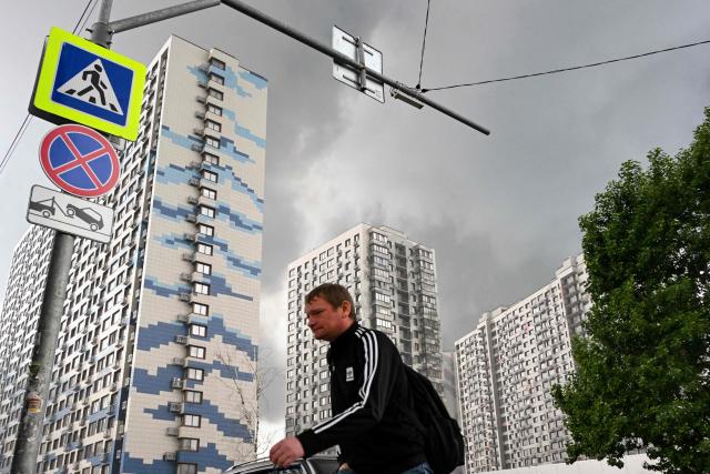 A man walks in a residential locality blanketed in smoke in Moscow on June 18, 2026. Moscow was fending off a "large-scale" drone attack from Ukraine, with several drones reaching an oil refinery, the city's mayor Sergey Sobyanin said early on June 18, 2026. (Photo by AFP)