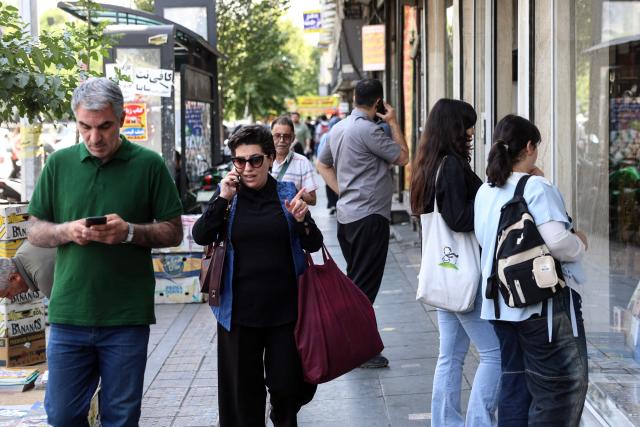 Iranians walk through a street in Tehran on June 18, 2026. The United States and Iran have signed a deal to end the Middle East war, with a ceremony set for June 19 in Switzerland that will mark the start of a 60-day negotiation period. The memorandum of understanding aims to put an end to months of conflict initiated by US-Israeli strikes on Iran in February, which wreaked chaos across the region and rattled the global economy. (Photo by AFP) / 
