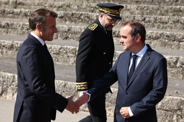 France's President Emmanuel Macron (L) shakes hands with France's Prime Minister Sebastien Lecornu (R) next to Prefect of the Hauts-de-Seine department Alexandre Brugère during the commemorative ceremony for the 86th anniversary of the Appeal of 18 June, in Mont Valerien on June 18, 2026. (Photo by SIMON WOHLFAHRT / POOL / AFP)