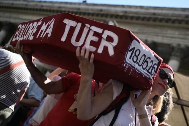 A protester holds a placard shaped as a coffin and reading "Bollore killed me", referring to French businessman Vincent Bollore, during a day of action called by journalists' unions to defend the news industry, at Place de la Bourse central Paris on June 18, 2026. (Photo by JULIEN DE ROSA / AFP)