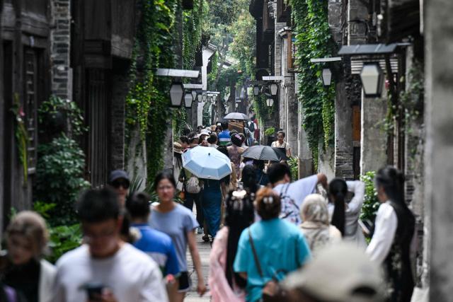 Visitors walk on a street in the scenic town of Wuzhen, in China’s eastern Zhejiang province on June 18, 2026. (Photo by Hector RETAMAL / AFP)