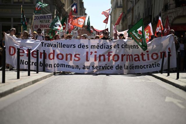 Protesters hold a banner reading "Media professionals and citizens, let's defend the news and information – our common good that sustains democracy" during a day of action called by journalists' unions to defend the news industry, at Place de la Bourse central Paris on June 18, 2026. (Photo by JULIEN DE ROSA / AFP)