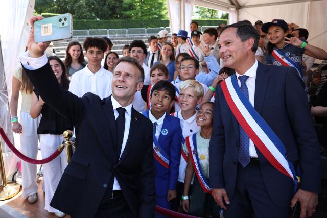 France's President Emmanuel Macron (L) poses for a selfie with guest children and Mayor of Mont Valerien Guillaume Boudy during the commemorative ceremony for the 86th anniversary of the Appeal of 18 June, in Mont Valerien on June 18, 2026. (Photo by SIMON WOHLFAHRT / POOL / AFP)