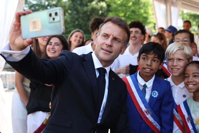France's President Emmanuel Macron (L) poses for a selfie with guest children during the commemorative ceremony for the 86th anniversary of the Appeal of 18 June, in Mont Valerien on June 18, 2026. (Photo by SIMON WOHLFAHRT / POOL / AFP)