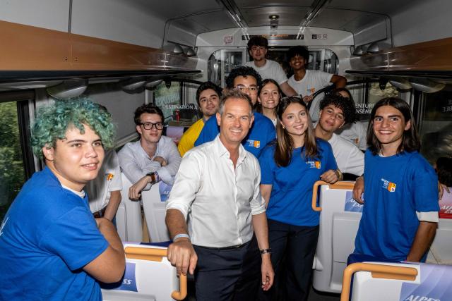 Edgar Grospiron (C), Chair of the French Alps 2030 Organising Committee, poses with volunteers on a train bound for Briançon on June 18, 2026, ahead of a ceremony to unveil the emblems for the French Alps 2030 Winter Olympic Games. (Photo by Miguel MEDINA / AFP)