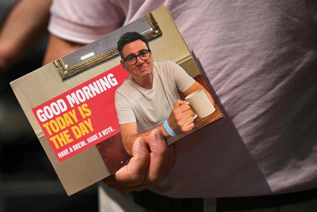 A Labour party supporter holds a leaflet depicting an image of the party's candidate Andy Burnham outside the Labour party campaign office in Ashton in Makerfield, northwest England, on June 18, 2026, as voters go to the polls to vote in the Makerfield by-election. Britain holds a unique vote on June 18 that could trigger the endgame for Labour leader Keir Starmer's beleaguered premiership, or win him a reprieve. (Photo by Oli SCARFF / AFP)
