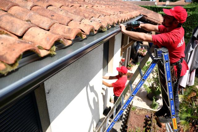 Workers install gutters on the roof of a house in Saint-Medard-en-Jalles, south-western France on June 18, 2026. A new heatwave swept across much of France on June 18, 2026, with temperatures forecast to approach 40C later in the week, dozens of trains cancelled and classes suspended. (Photo by ROMAIN PERROCHEAU / AFP)