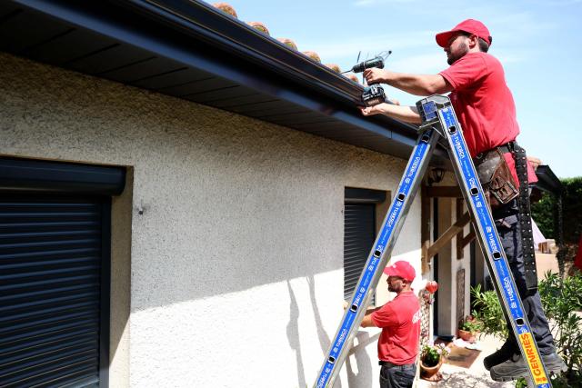 Workers install gutters on the roof of a house in Saint-Medard-en-Jalles, south-western France on June 18, 2026. A new heatwave swept across much of France on June 18, 2026, with temperatures forecast to approach 40C later in the week, dozens of trains cancelled and classes suspended. (Photo by ROMAIN PERROCHEAU / AFP)