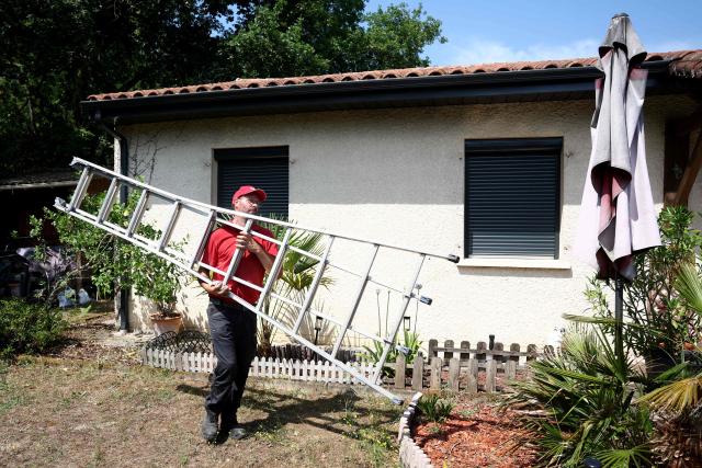 A worker carries a ladder after installing a gutter on the roof of a house in Saint-Medard-en-Jalles, south-western France on June 18, 2026. A new heatwave swept across much of France on June 18, 2026, with temperatures forecast to approach 40C later in the week, dozens of trains cancelled and classes suspended. (Photo by ROMAIN PERROCHEAU / AFP)