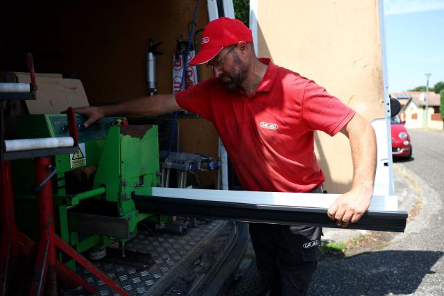 A worker removes a gutter from a machine before installing it in Saint-Medard-en-Jalles, south-western France on June 18, 2026. A new heatwave swept across much of France on June 18, 2026, with temperatures forecast to approach 40C later in the week, dozens of trains cancelled and classes suspended. (Photo by ROMAIN PERROCHEAU / AFP)