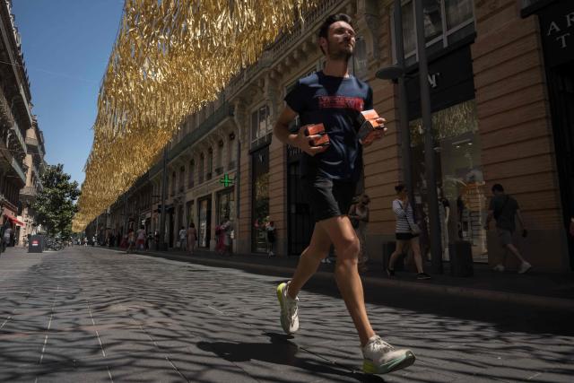 A runner jogs along a street covered by an installation to provide shade from the sun, in Toulouse on June 18, 2026. (Photo by Ed JONES / AFP)