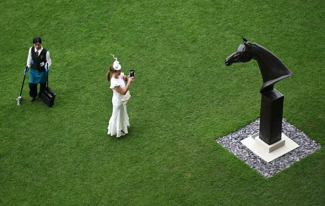 TOPSHOT - A racegoer photographs a statue of the horse 'Enable' as they attend the third day of the Royal Ascot horse racing meeting in Ascot, west of London, on June 18, 2026. (Photo by JUSTIN TALLIS / AFP)