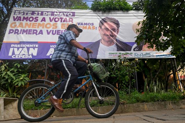 A man rides a bicycle in front of a billboard of presidential canditate Ivan Cepeda, of the Pacto Historico party, for the upcoming presidential election in Cali, Colombia, on June 18, 2026. Colombians vote on June 21, 2026 in a presidential runoff pitting a hard-right opera-singer-turned-lawyer against a leftist senator, an election with stark consequences for the country's stumbling peace process with armed groups and strained ties with Washington. (Photo by JOAQUIN SARMIENTO / AFP)