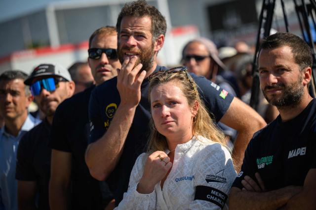Skippers of the Vendee Arctique solo sailing race (RtoL), Italy's Ambrogio Beccaria, France's Elodie Bonafous, France's Nico D'Estais and British Sam Goodchild pay homage to late French skipper Charlie Dalin, before the podium ceremony of the race, in Les Sables-d'Olonne on June 18, 2026. French offshore sailor and Vendee Globe 2024/2025 winner Charlie Dalin has died in Quimper, western France, aged 42, from cancer, his family announced on June 11, 2026. (Photo by Loic VENANCE / AFP)