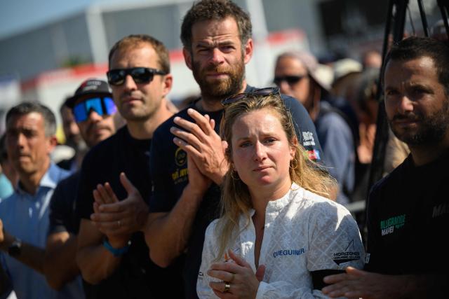 Skippers of the Vendee Arctique solo sailing race (RtoL), Italy's Ambrogio Beccaria, France's Elodie Bonafous, France's Nico D'Estais and British Sam Goodchild pay homage to late French skipper Charlie Dalin, before the podium ceremony of the race, in Les Sables-d'Olonne on June 18, 2026. French offshore sailor and Vendee Globe 2024/2025 winner Charlie Dalin has died in Quimper, western France, aged 42, from cancer, his family announced on June 11, 2026. (Photo by Loic VENANCE / AFP)