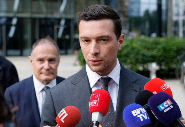 Jordan Bardella, French far-right Rassemblement National (RN) party's President, member of the European Parliament and president of the Patriots for Europe (PfE) group speaks to journalists in front of the Frontex, the European Border and Coast Guard Agency building next to Rassemblement National (RN) party member and former head of the EU's border agency Frontex Fabrice Leggeri in Warsaw, Poland on June 18, 2026. Jordan Bardella is in Warsaw to meet with leaders of Polands far right, marking the latest stop on his overseas tour aimed at strengthening his European alliances just a few months before the French presidential election. (Photo by Wojtek RADWANSKI / AFP)